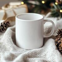 Cozy white mug resting on knitted blanket surrounded by pine cones and warm lights photo