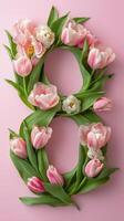 Floral arrangement of pink tulips shaped like the number eight on a pastel background photo