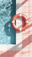 Bright and colorful lifebuoy hanging on pink tiled wall above clear swimming pool water photo