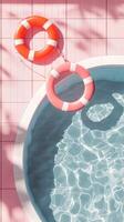 Bright and colorful lifebuoy hanging on pink tiled wall above clear swimming pool water photo