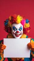 Colorful clown with vibrant wig holds sign in front of bright pink background photo