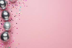 Shimmering disco balls glisten on a pink surface with confetti scattered around photo