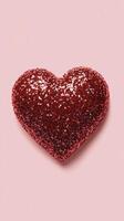 Shiny red heart shaped decoration on soft pink background for festive occasions photo