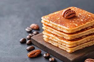 Stack of fluffy pancakes with pecans on a wooden board against a dark background photo
