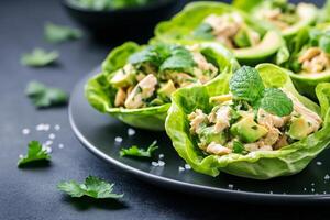 Fresh chicken salad served in lettuce cups with avocado and cilantro garnish for healthy dining photo