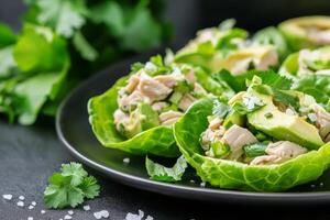 Fresh chicken salad served in lettuce cups with avocado and cilantro garnish for healthy dining photo