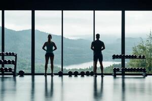 Two individuals exercising in a gym with scenic mountain views in the background photo