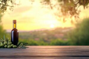 Olive oil bottle and olives on wooden table at sunset over distant hills photo