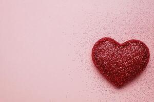 Glittering red heart decoration on a soft pink background for celebrations and events photo