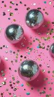 Colorful disco balls and confetti on a vibrant pink background for a festive celebration photo