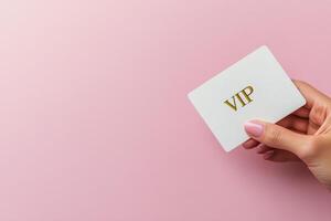 Elegant hand holding a stylish VIP card against a soft pink background photo