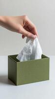 Hand reaching into a green tissue box to pull out a paper tissue for use photo