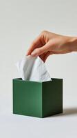 Hand reaching into a green tissue box to pull out a paper tissue for use photo