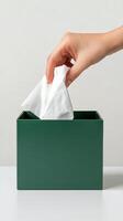 Hand reaching into a green tissue box to pull out a paper tissue for use photo