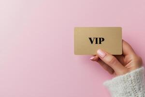 Elegant hand holding a stylish VIP card against a soft pink background photo