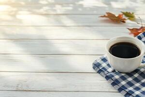 Warm coffee cup resting on a checkered napkin surrounded by autumn leaves photo