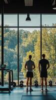 Two individuals enjoying a workout view from a gym overlooking a lush green landscape photo