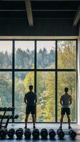 Two individuals enjoying a workout view from a gym overlooking a lush green landscape photo