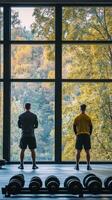 Two individuals enjoying a workout view from a gym overlooking a lush green landscape photo