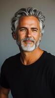 Mature man with salt and pepper hair poses confidently in a casual black shirt indoors photo