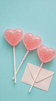 Three heart shaped lollipops with sparkling finish on a light blue background photo