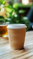 Coffee cup on wooden table surrounded by greenery in a cozy cafe setting during the afternoon photo
