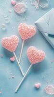 Three heart shaped lollipops with sparkling finish on a light blue background photo