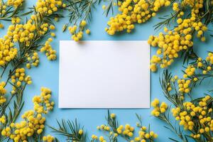 Bright yellow flowers surrounding a blank white card on a textured blue background photo