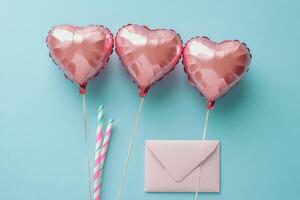 Heart shaped balloons and a pink envelope on a light blue background for celebration photo