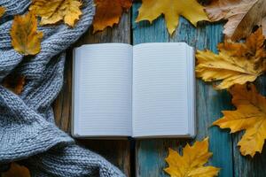 Cozy autumn setting with an open notebook surrounded by yellow leaves and a warm scarf photo