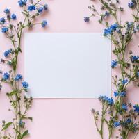 Beautiful spring flowers frame a blank card on a pink background for creative projects photo