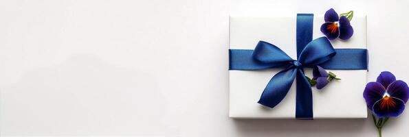 Elegant gift box wrapped in blue ribbon with flowers on a light background photo