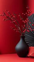 Elegant arrangement of red berries in a black vase with a fan on a vibrant red background photo