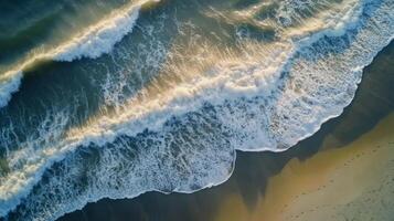 Waves crashing on a sandy shore with vibrant colors during sunset photo