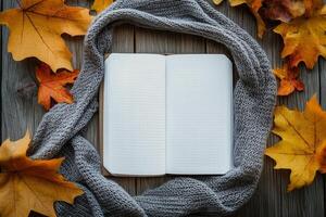 Cozy autumn setting with an open notebook surrounded by yellow leaves and a warm scarf photo