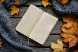 Cozy autumn setting with an open notebook surrounded by yellow leaves and a warm scarf photo