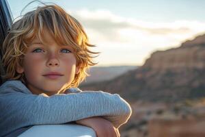 Young boy gazing out of a window with scenic mountain view in the background during daytime photo