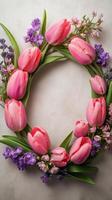 Delicate floral wreath with pink tulips and purple blooms on wooden surface photo