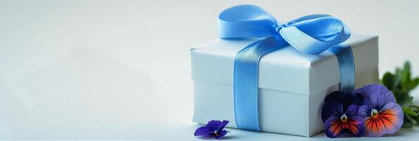 Elegant gift box wrapped in blue ribbon with flowers on a light background photo