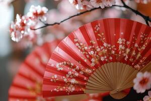 Red fan with floral design surrounded by cherry blossoms in springtime photo