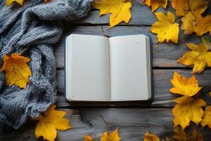Cozy autumn setting with an open notebook surrounded by yellow leaves and a warm scarf photo