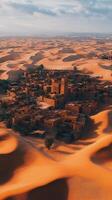 Scenic view of a desert oasis village surrounded by golden sand dunes at sunset photo
