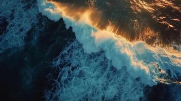 Waves crashing on a sandy shore with vibrant colors during sunset photo