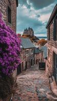 Charming cobblestone street lined with vibrant flowers in a historic village with castle backdrop photo