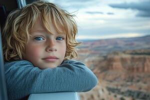 Young boy gazing out of a window with scenic mountain view in the background during daytime photo