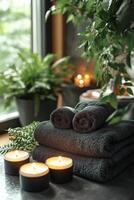 Soft white towels stacked near lit candles in a relaxing indoor setting with plants photo