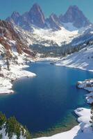 Serene mountain lake surrounded by snow capped peaks and lush forest in daytime photo