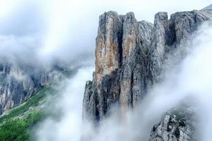 A mountain with tall rock formations in the clouds photo