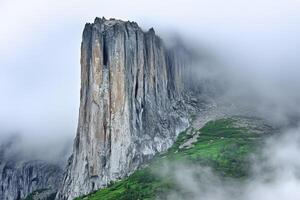 A mountain with a tall rock in the clouds photo