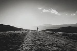 A person standing on a hill in the middle of a field photo